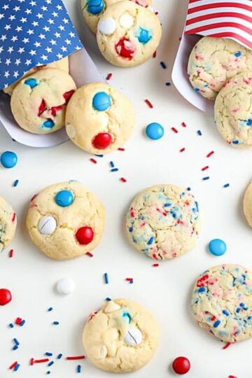 overhead shot of patriotic cookies in red white and blue bags surrounded by festive sprinkles for recipe card