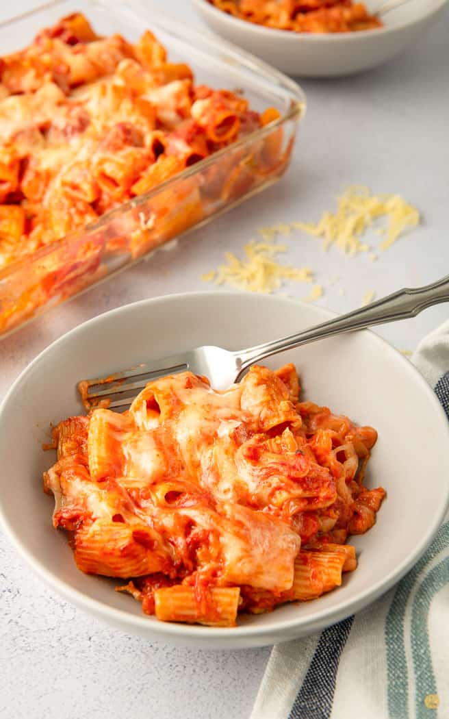 baked rigatoni in a white bowl with a fork