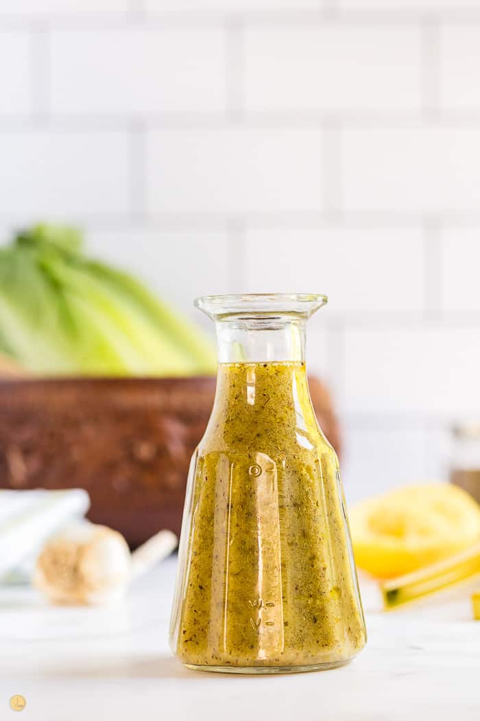 salad dressing in a cruet with white tile in the background