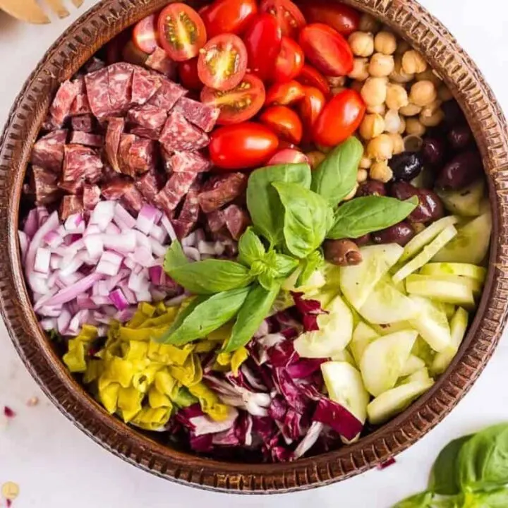 overhead picture of italian chopped salad with layered toppings in a wood bowl