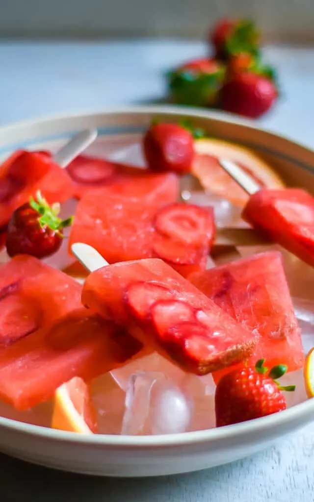 bowl of popsicles on ice with strawberry garnishes