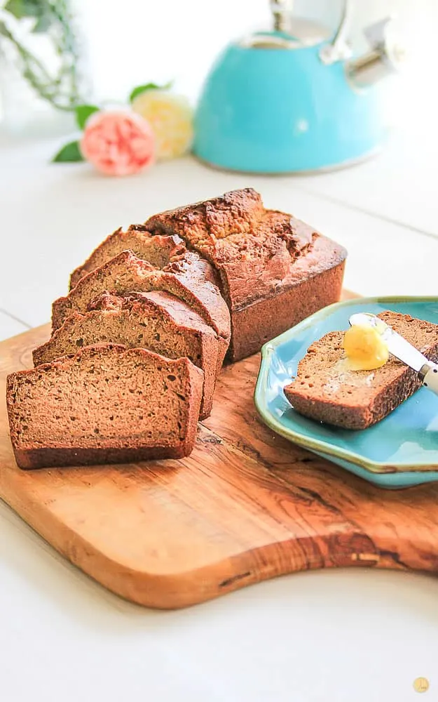 slices of bread loaf on a wood cutting board with a butter spreader