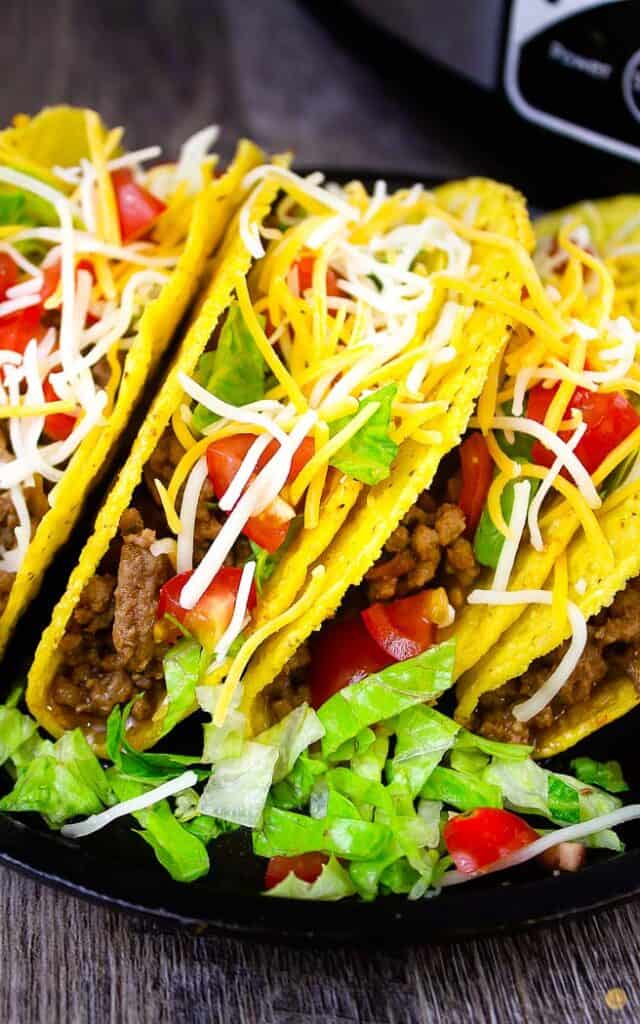 black plate with three tacos on it