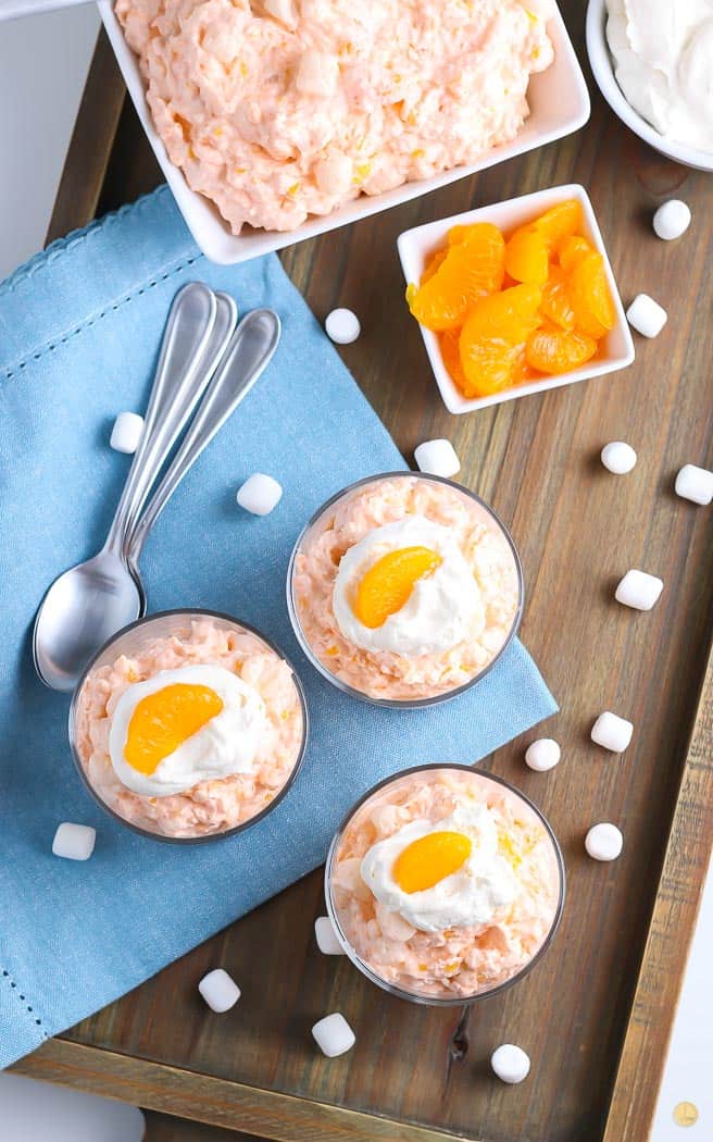 overhead picture of three small bowls of orange salad with mini marshmallows on the table