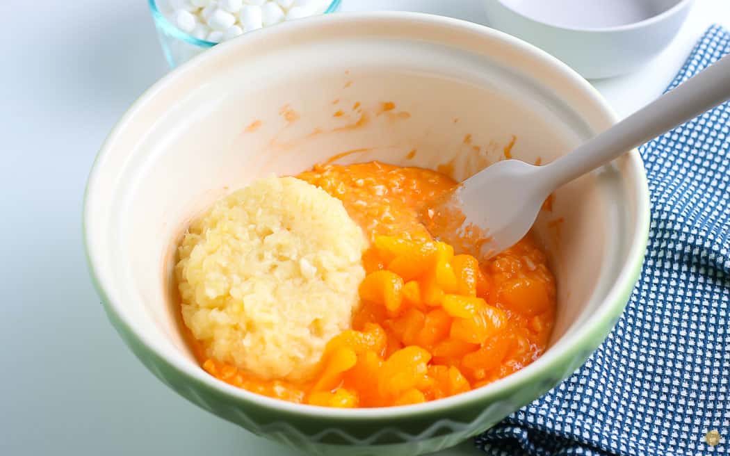 orange cottage cheese topped with oranges and pineapple in a bowl