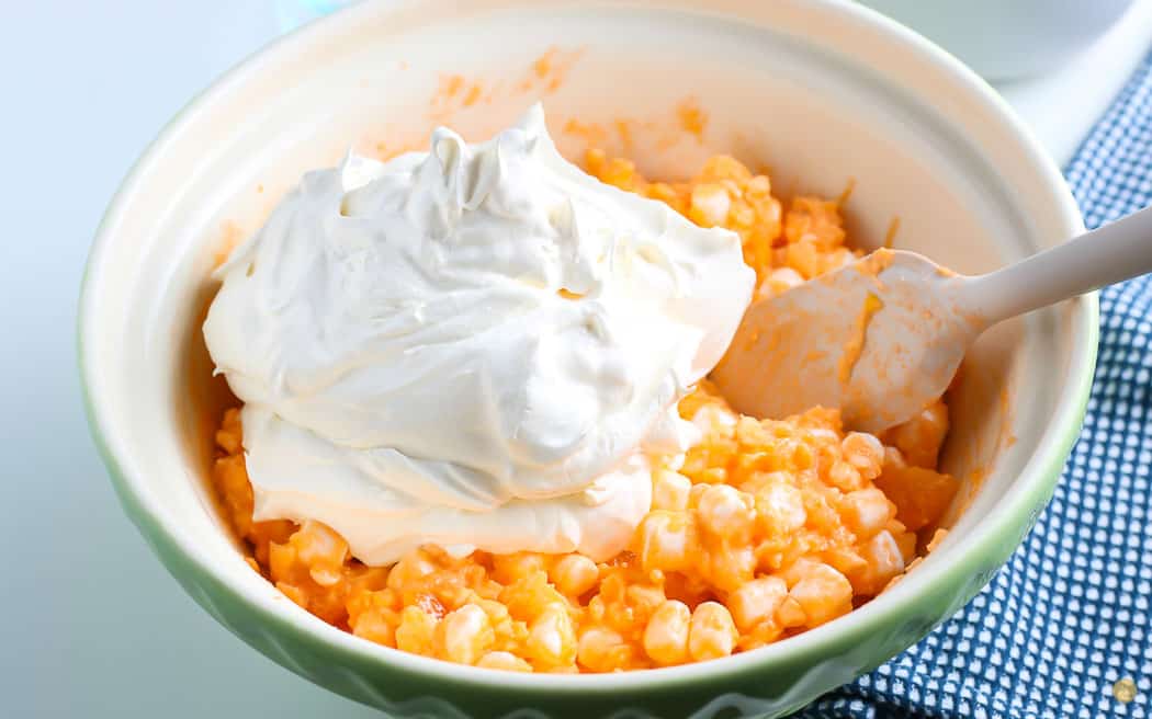 cool whip on top of orange salad with a spatula