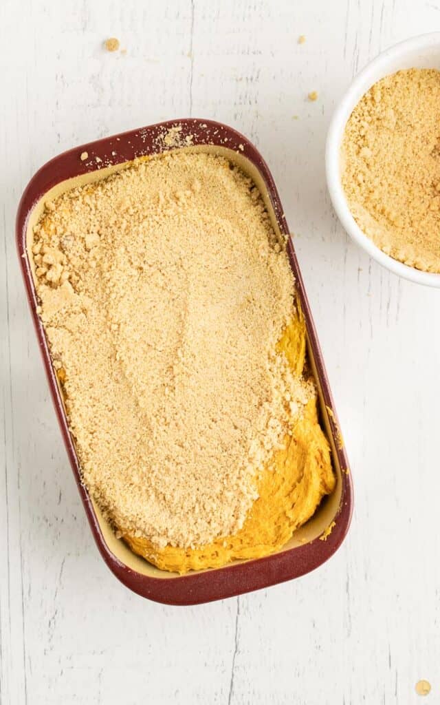 pumpkin bread batter in loaf pan covered in streusel top
