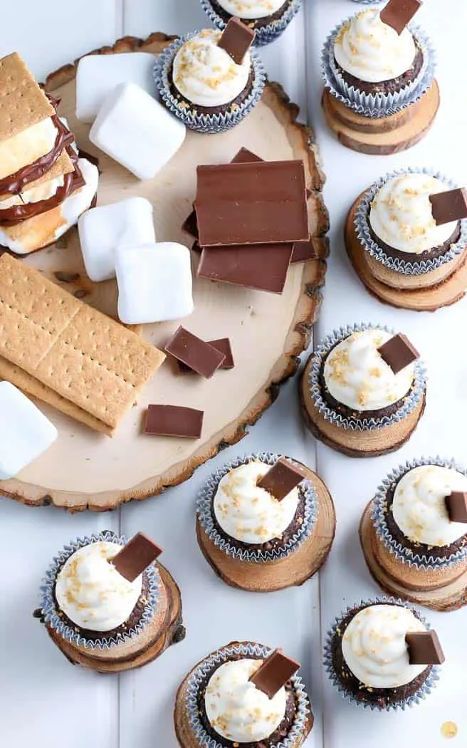 smores cupcakes on a white board with smore toppings on the left