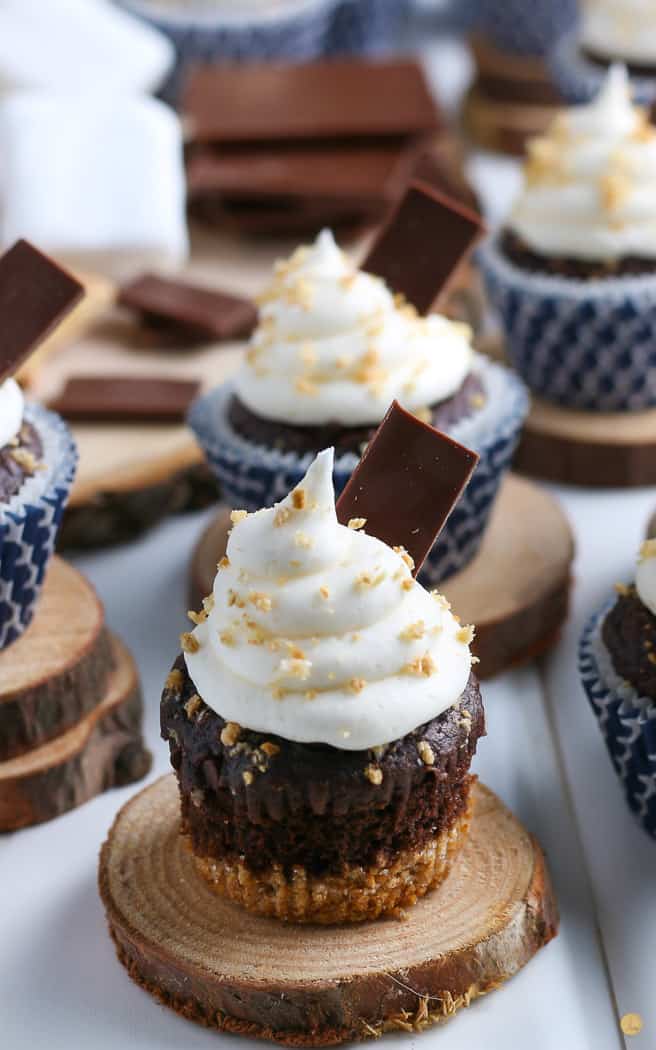 unwrapped chocolate cupcake with marshmallow frosting on a wood circle