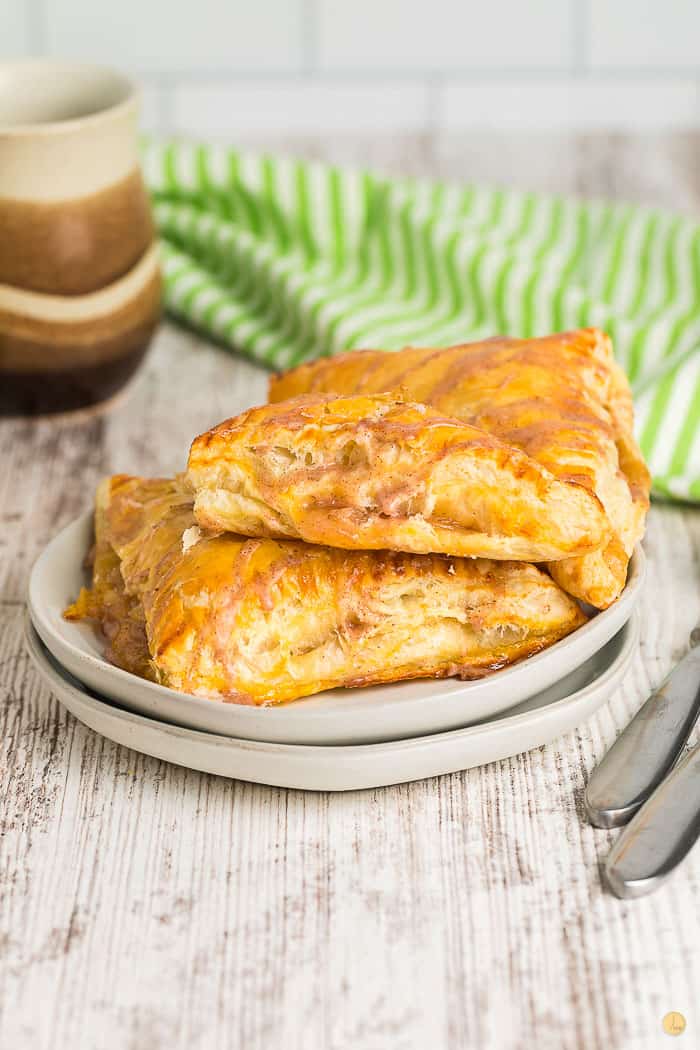 two apple turnovers on a stack of grey plates