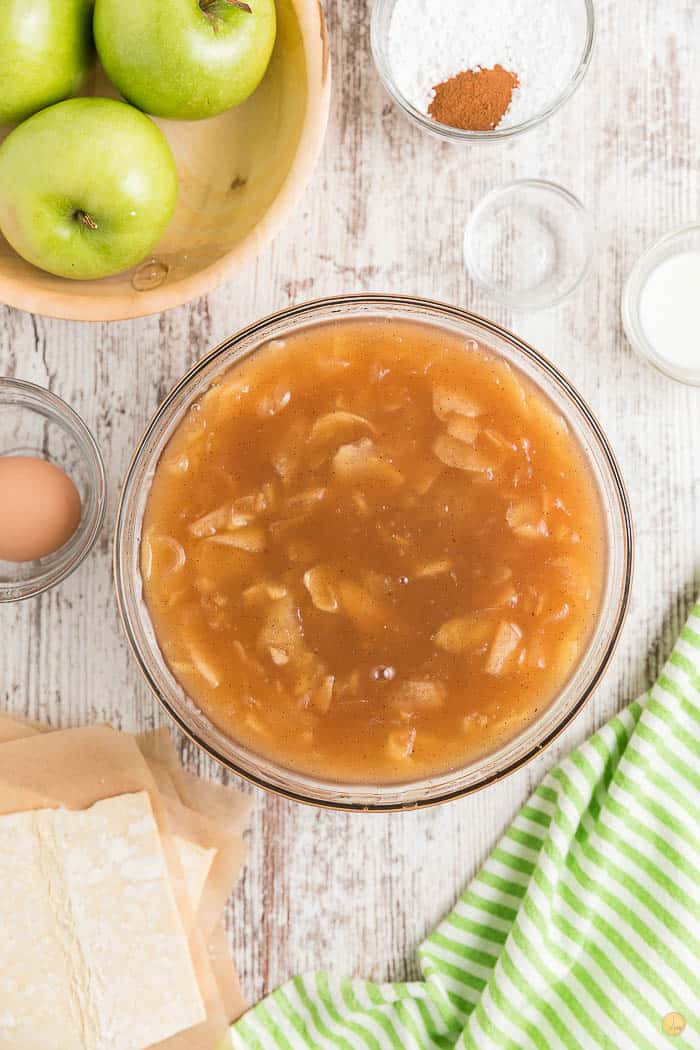 apple pie filling in a clear bowl on a white backdrop