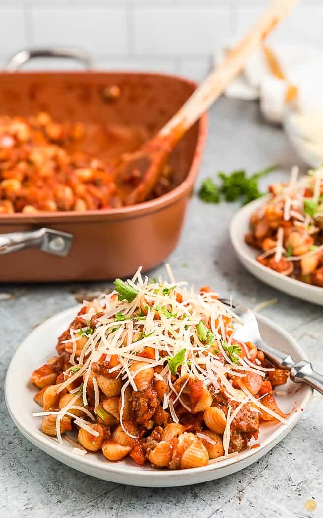 beefaroni on a white plate covered with shredded cheese