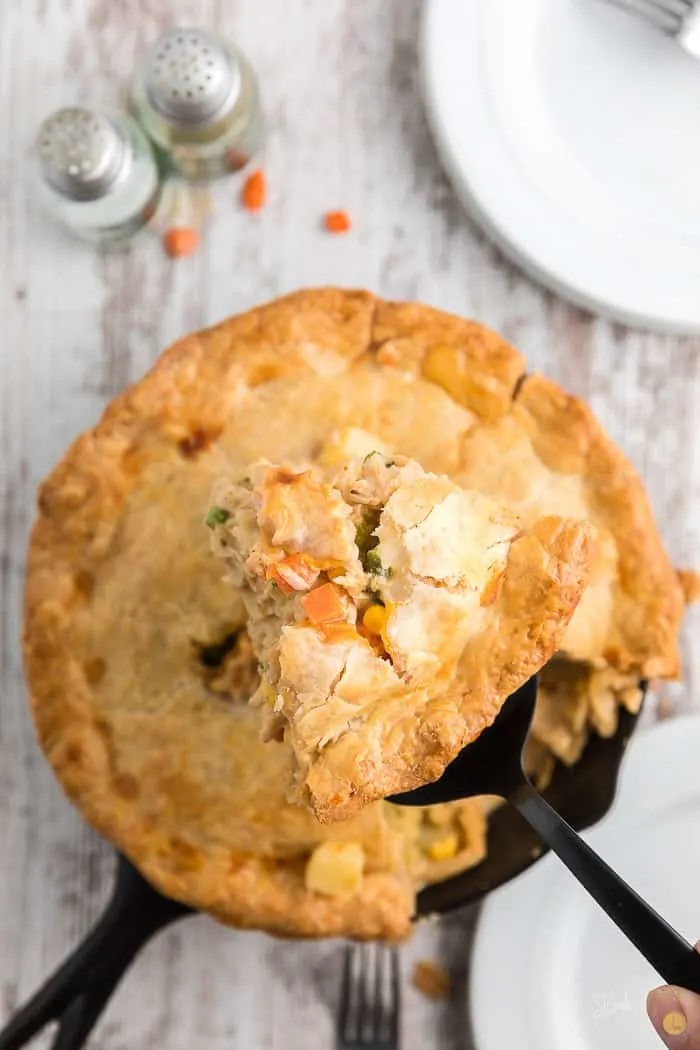 Slice of chicken pot pie hovering over a full pot pie