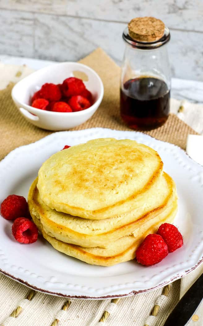 old fashioned pancakes on a white plate with raspberries