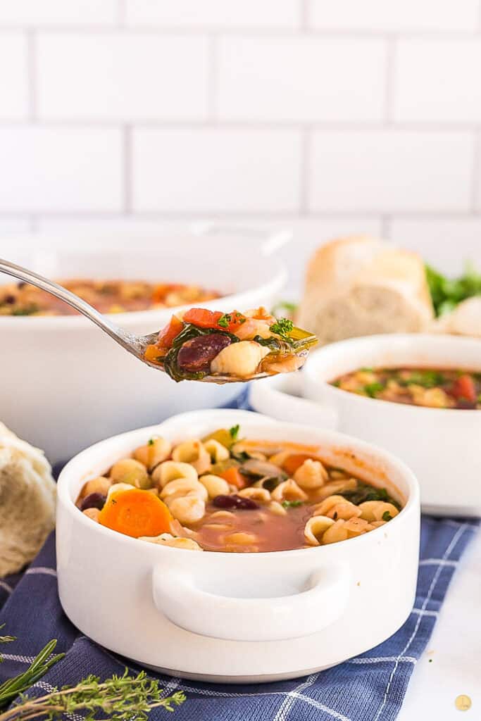 spoon full of soup over a white bowl of soup