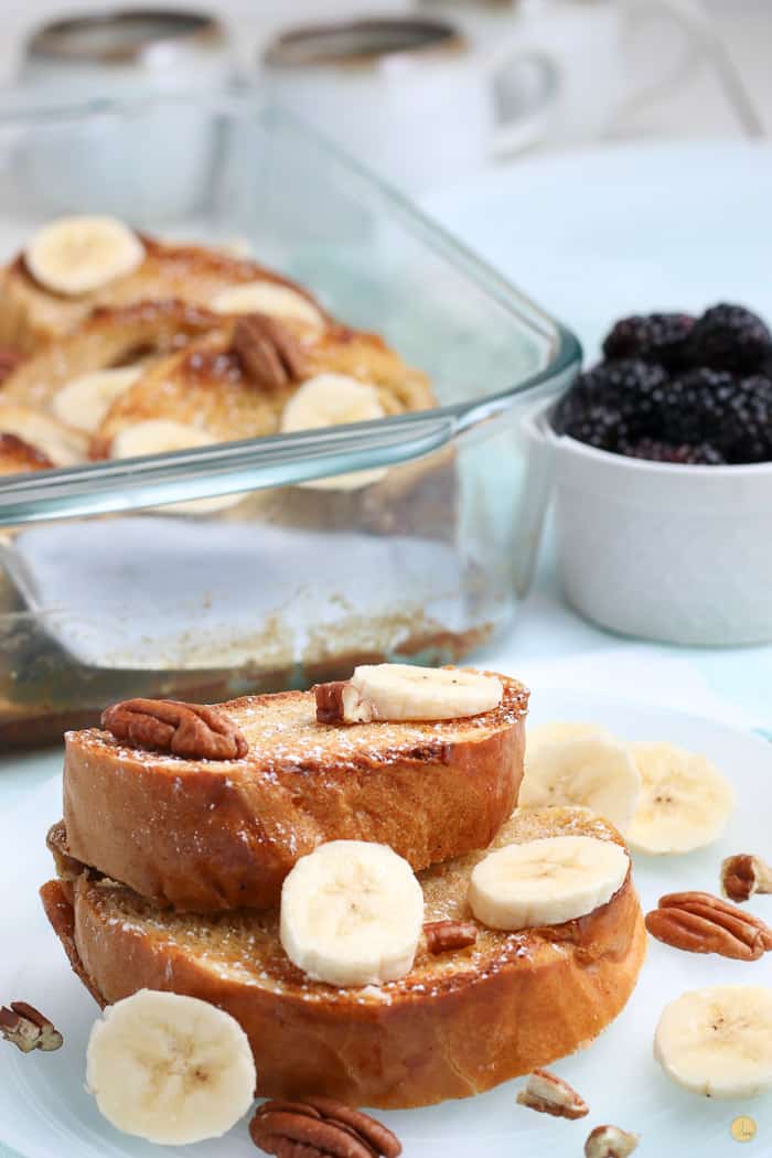 two slices of french toast with bananas and pecans