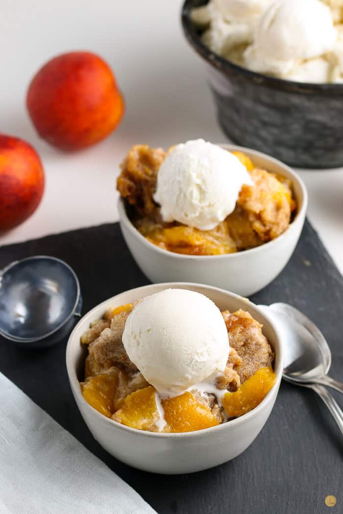 two bowls of crock pot cobbler topped with vanilla ice cream