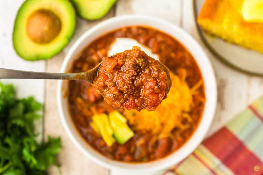 close up of spoon of chili hovering over a bowl