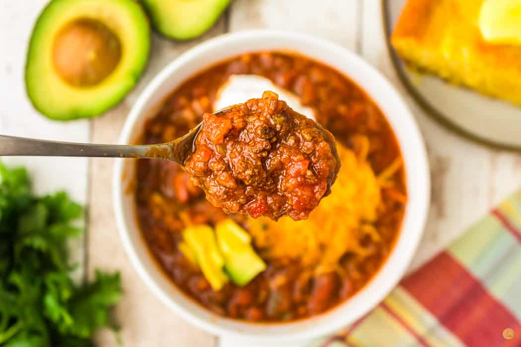 close up of spoon of chili hovering over a bowl