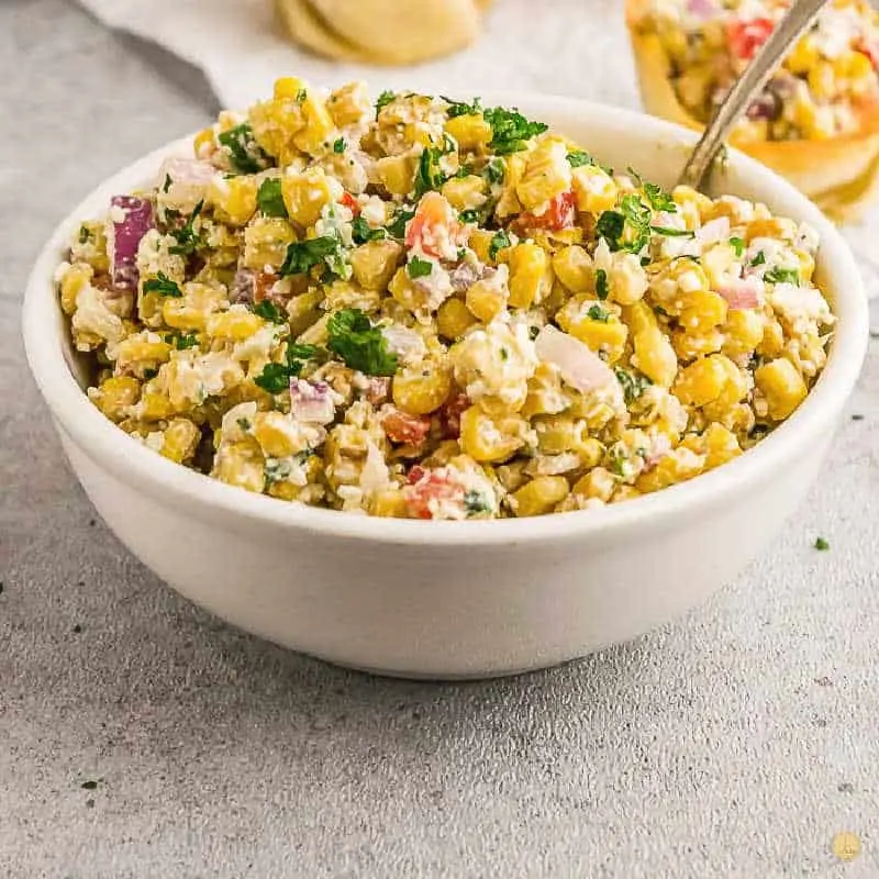 square photo of corn salad in a white bowl