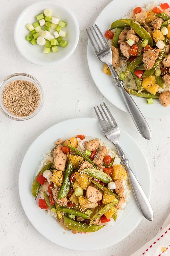 two plates of sweet and sour chicken with forks