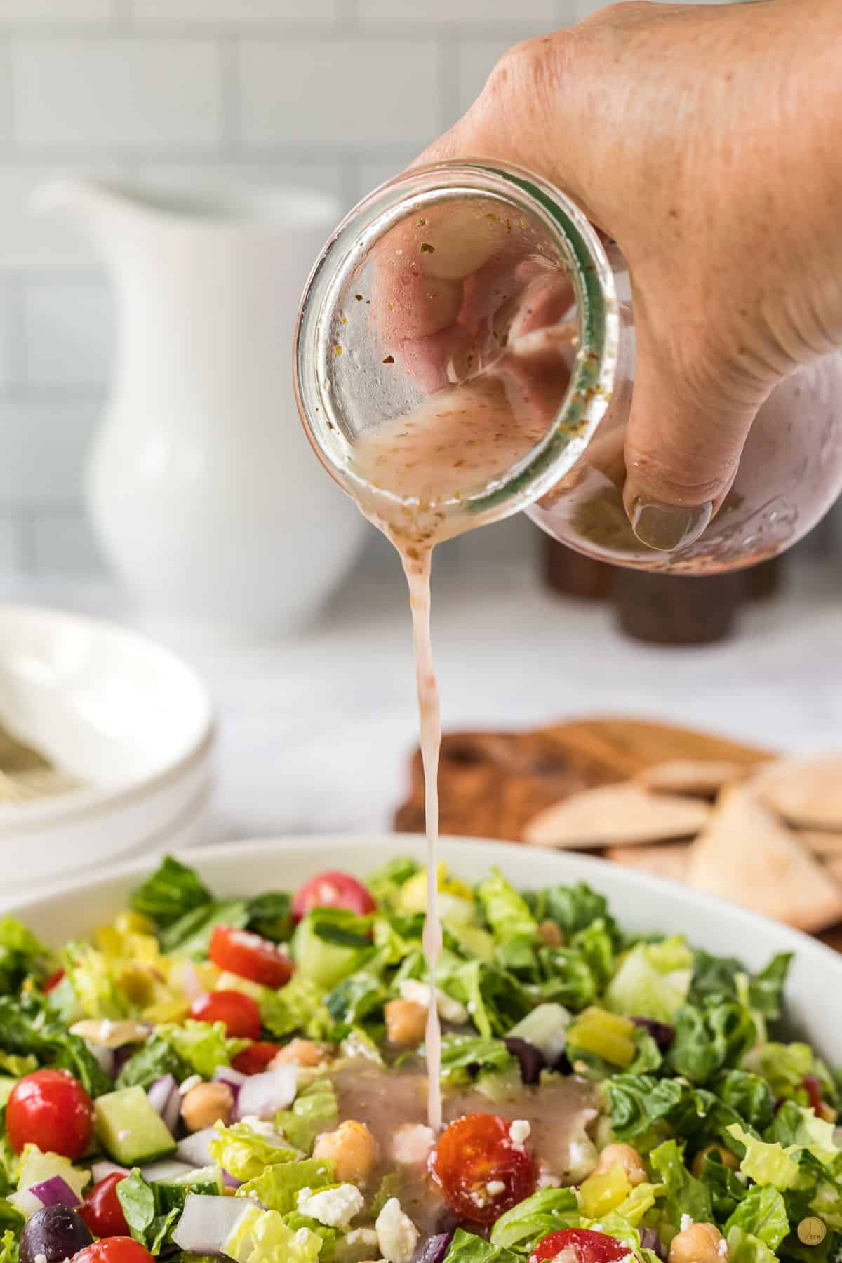 bottle pouring dressing onto a salad