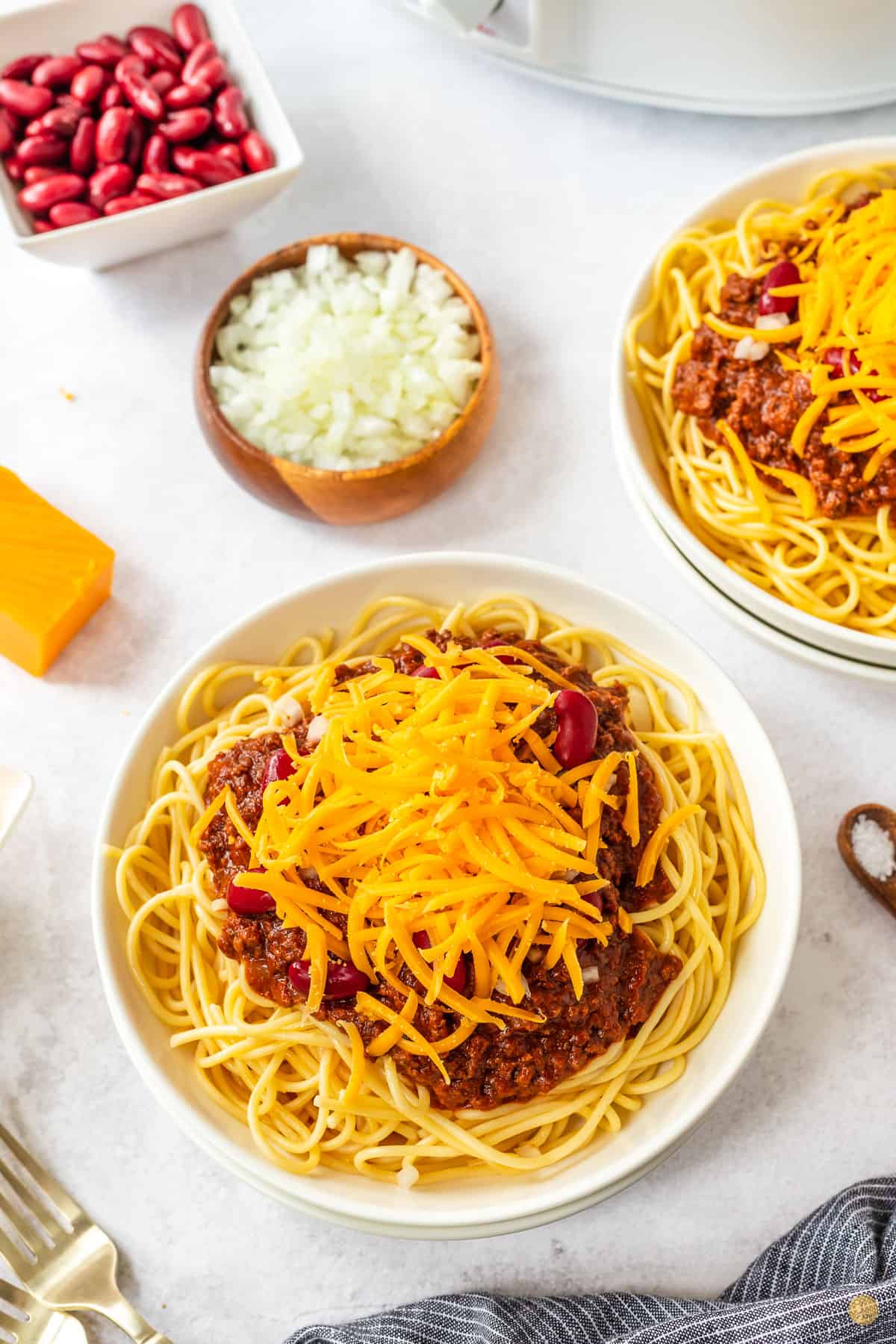bowl of chili, spaghetti, beans, onion, and cheese