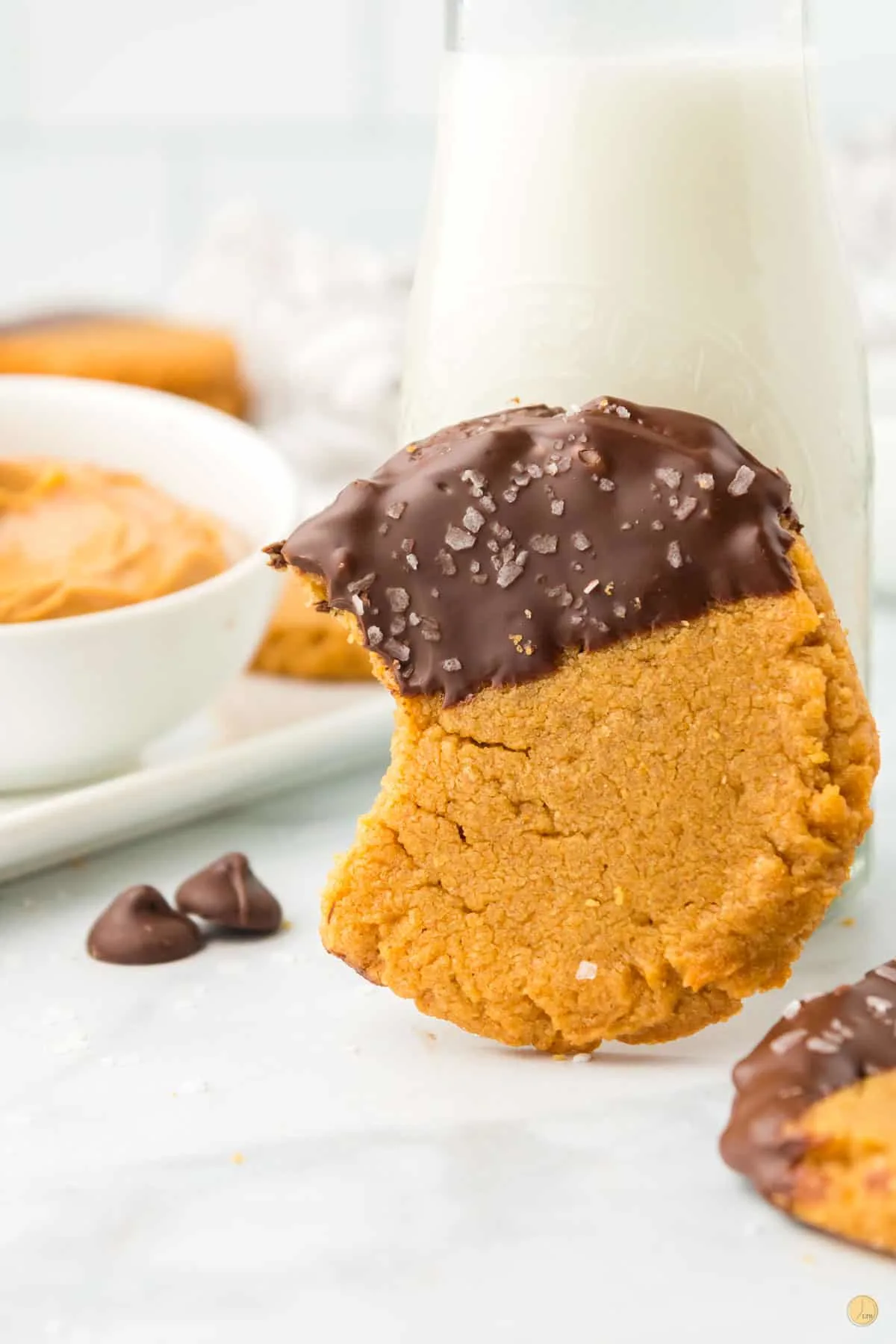 peanut butter cookie with bite missing and a glass of milk