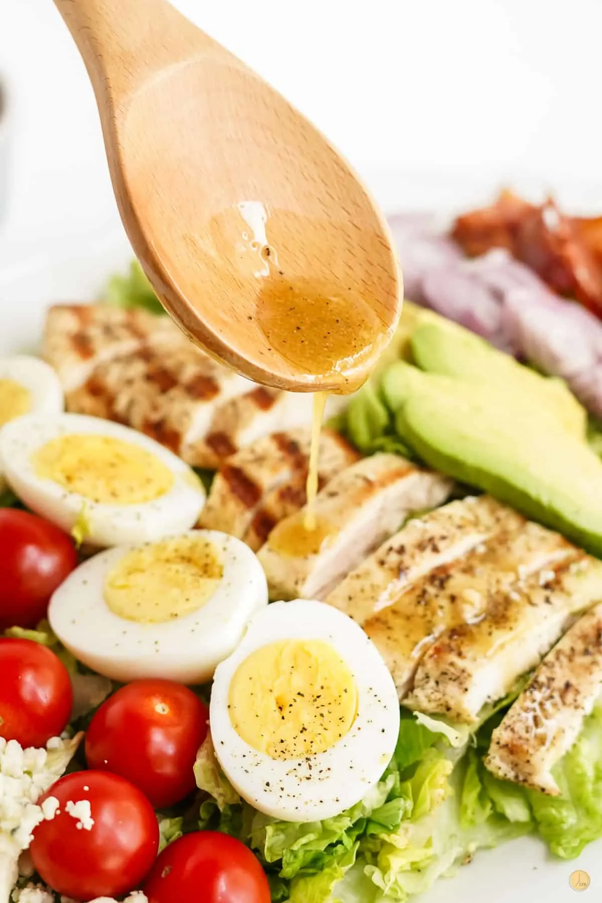 spoon drizzling salad dressing on eggs