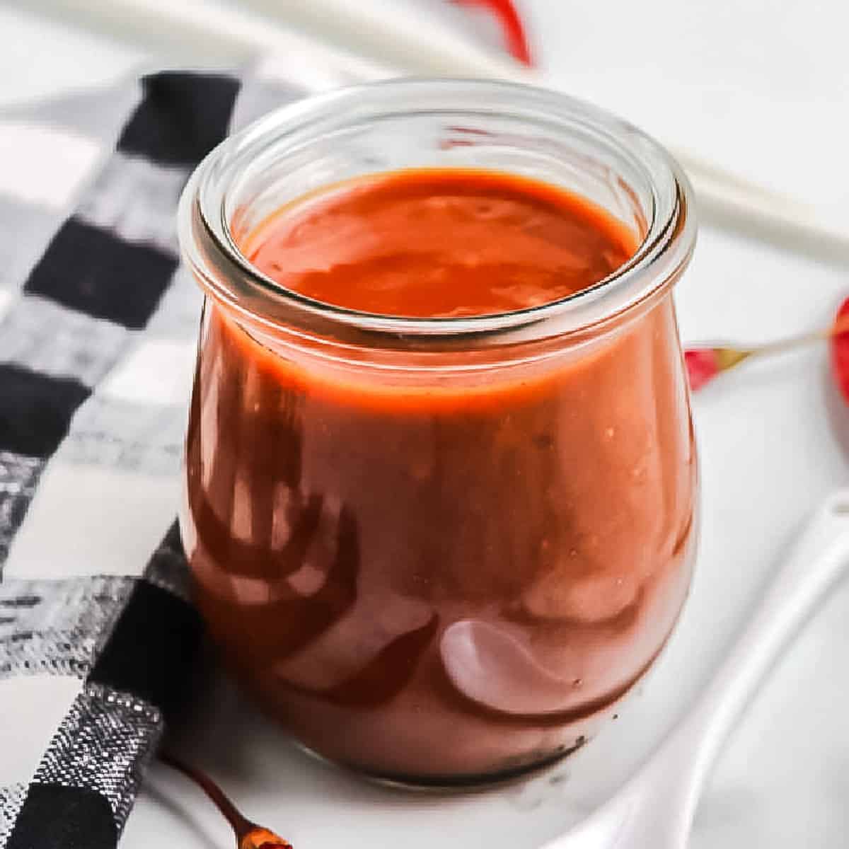 close up of jar of sauce on black and white napkin