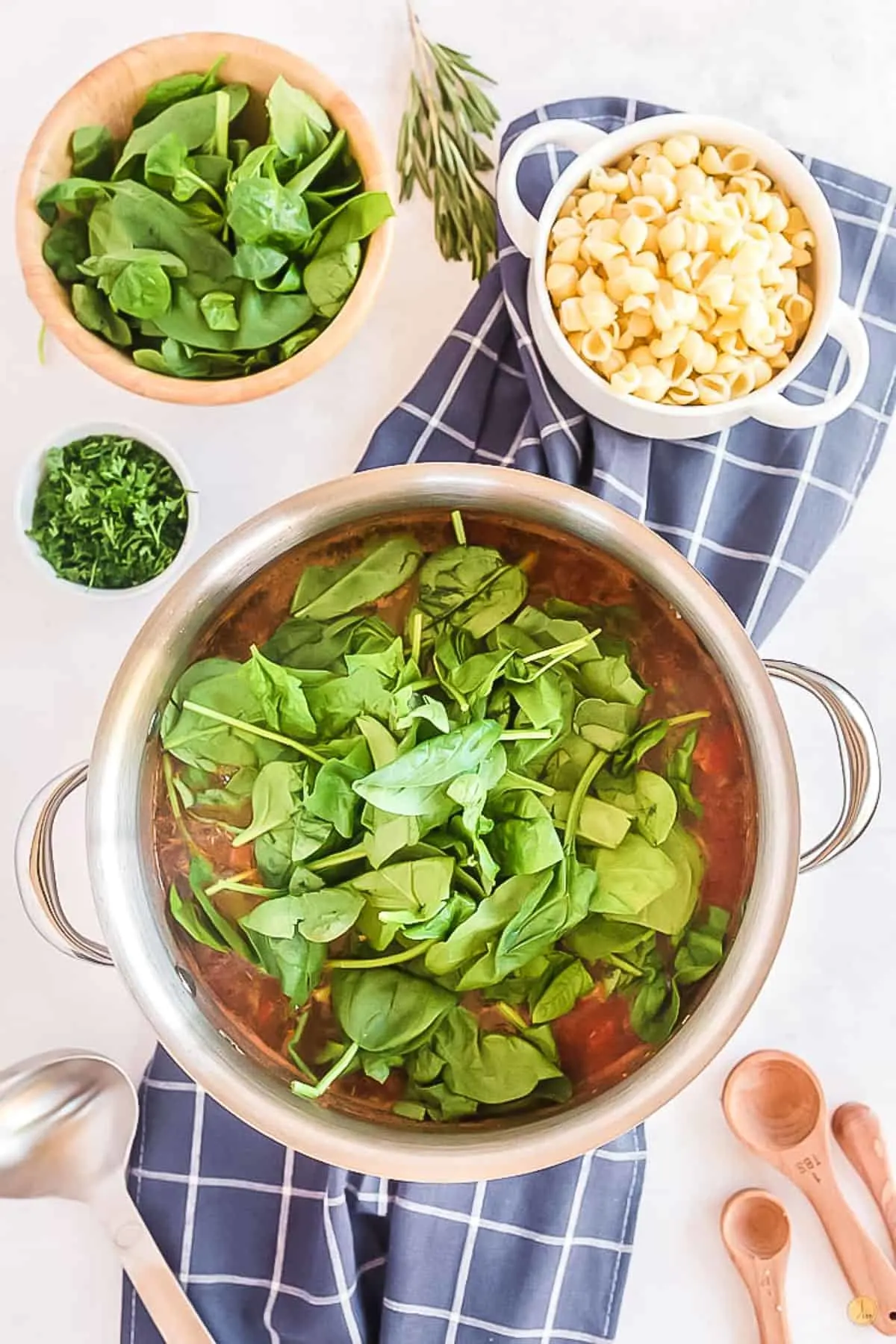 metal pot with soup and fresh spinach on a blue napkin