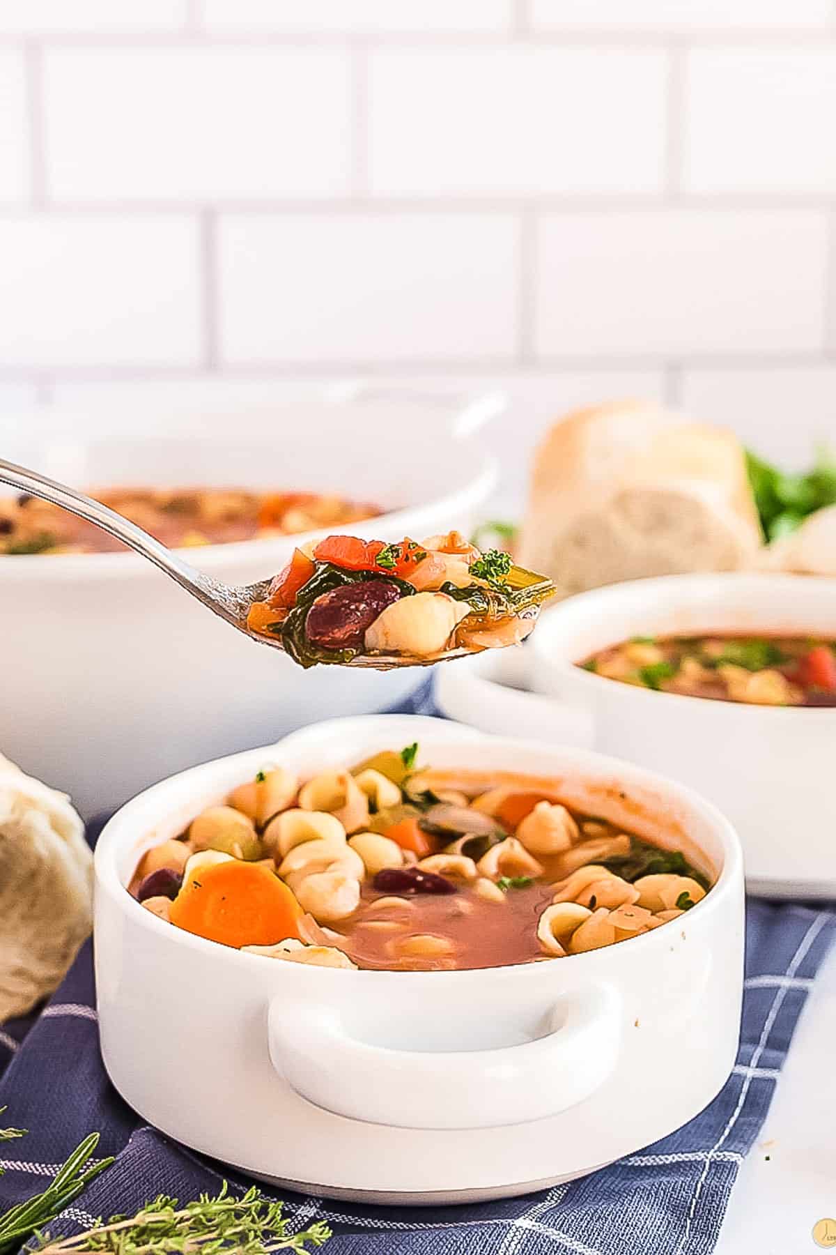 spoon full of italian minestrone soup over a white bowl of soup