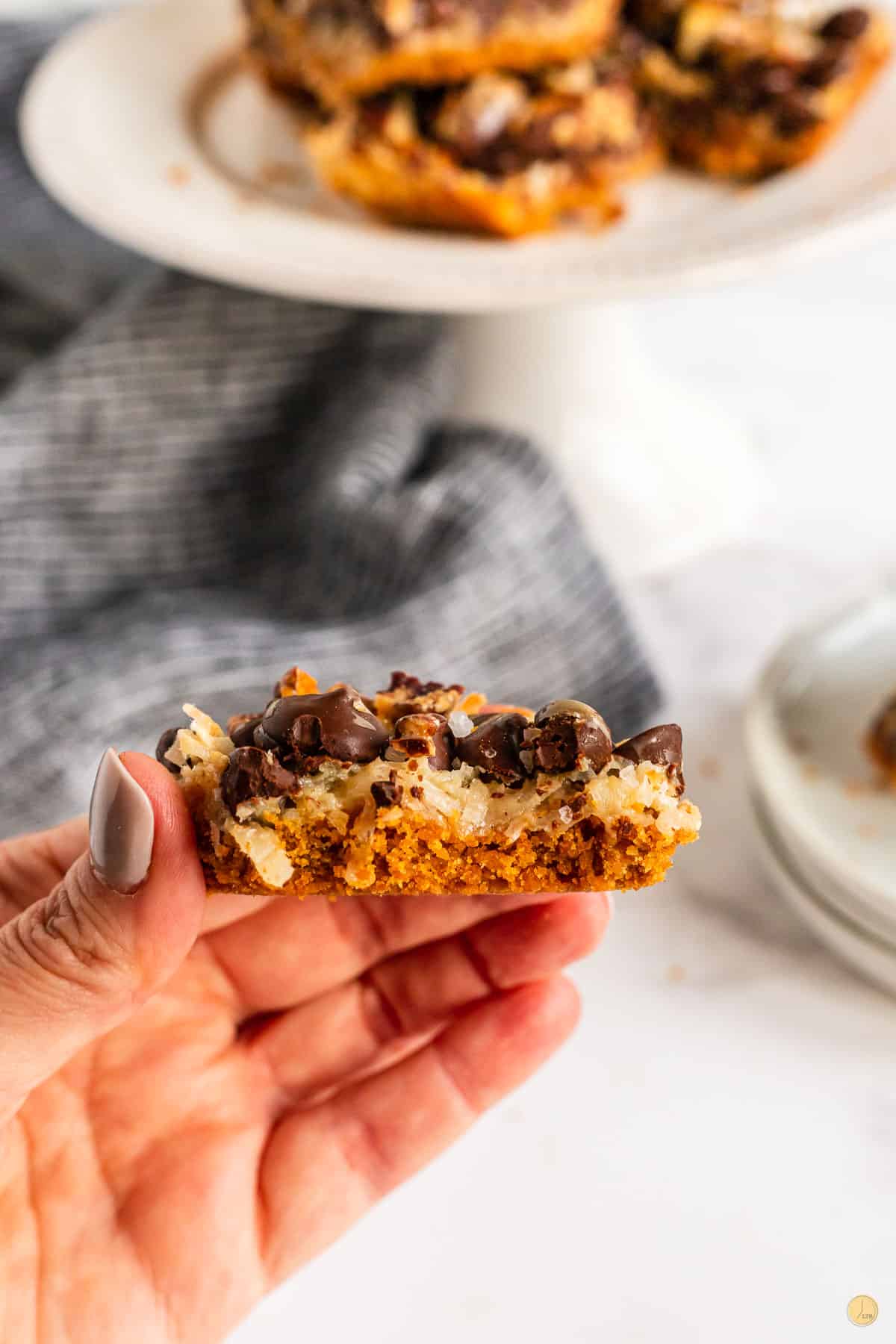 hand holding 7 layer bar with bite taken out of it