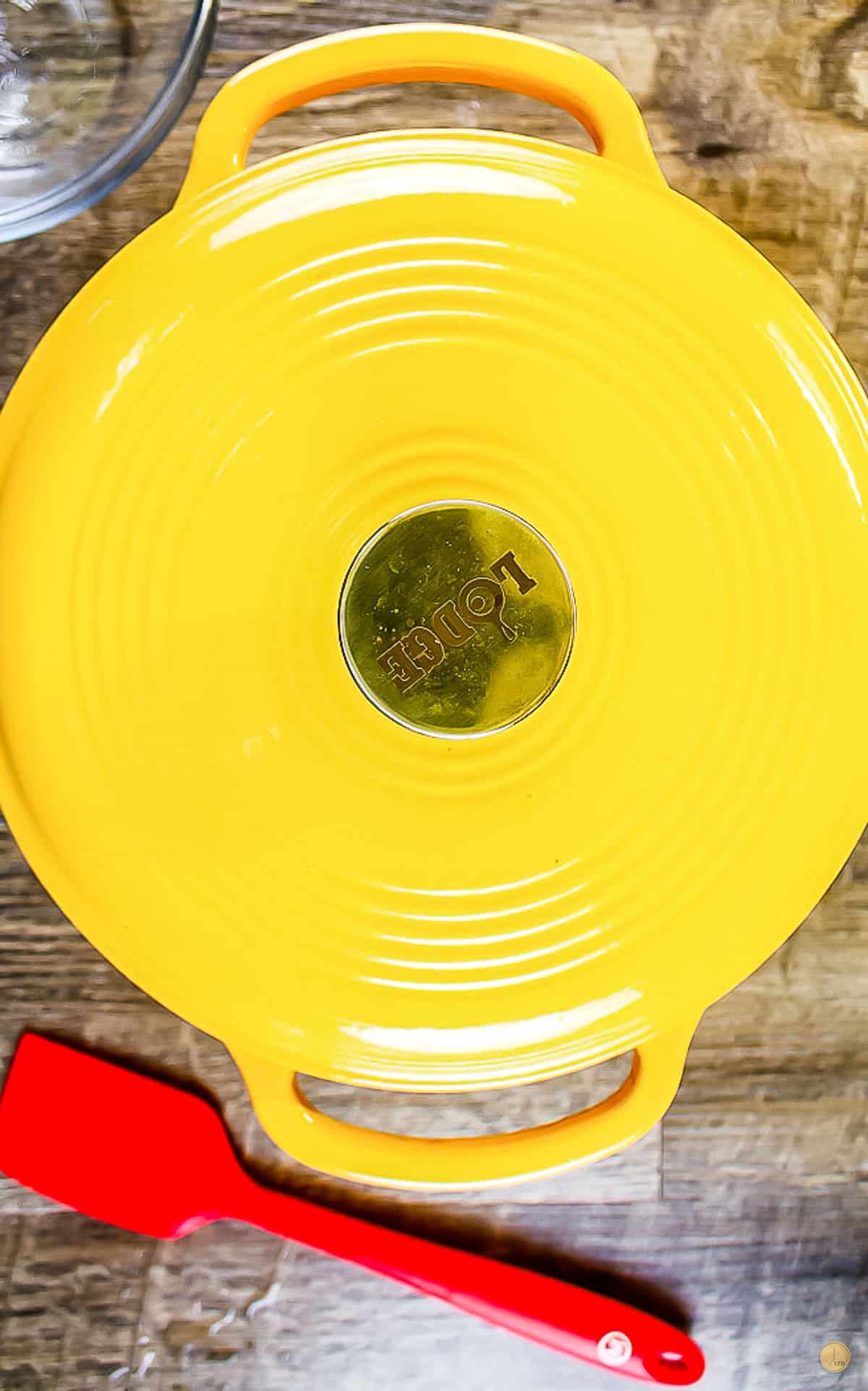 covered yellow dutch oven with a red spatula on the left