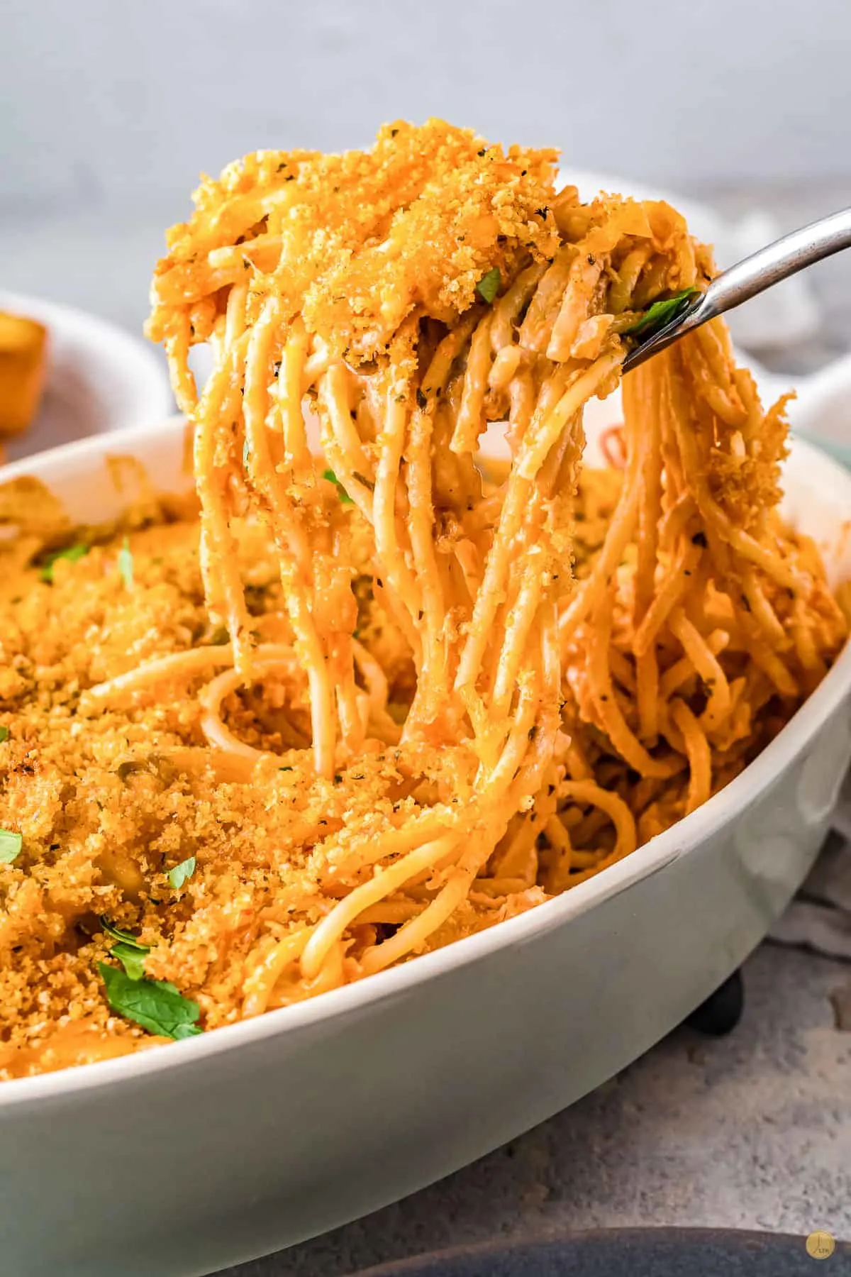 spoon scooping out chicken tetrazzini out of a white bowl