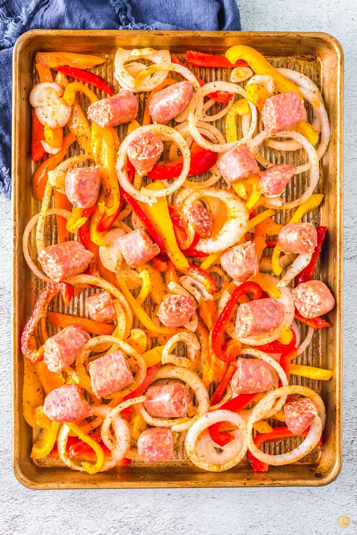 sausage peppers and onions on a baking sheet