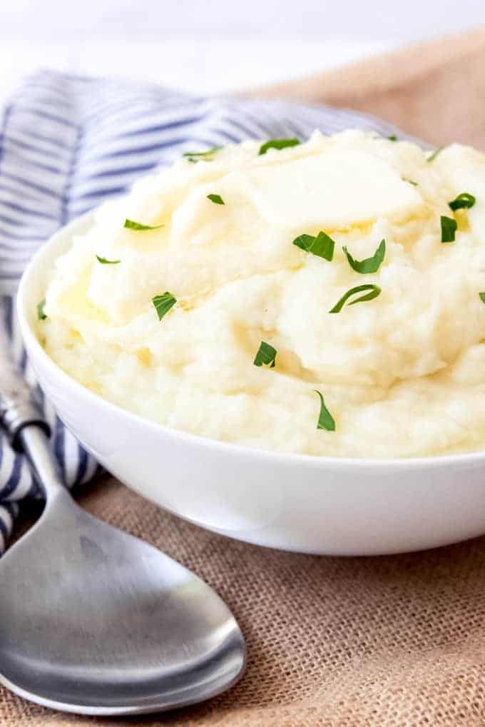 bowl of mashed potatoes with sliced green onions and a blue napkin
