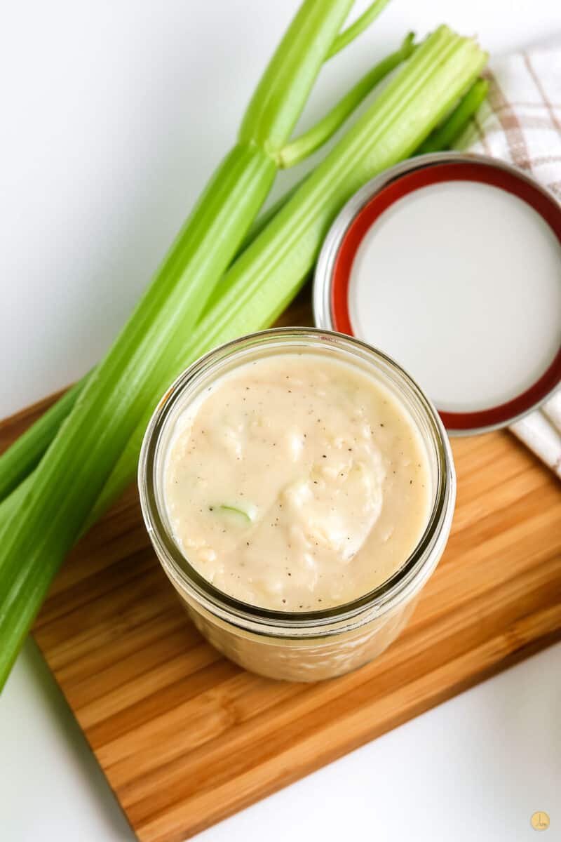 jar of soup with stalks of celery