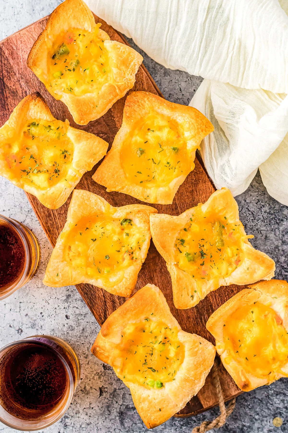 wood tray with mini chicken pot pies on it and two glasses of cola