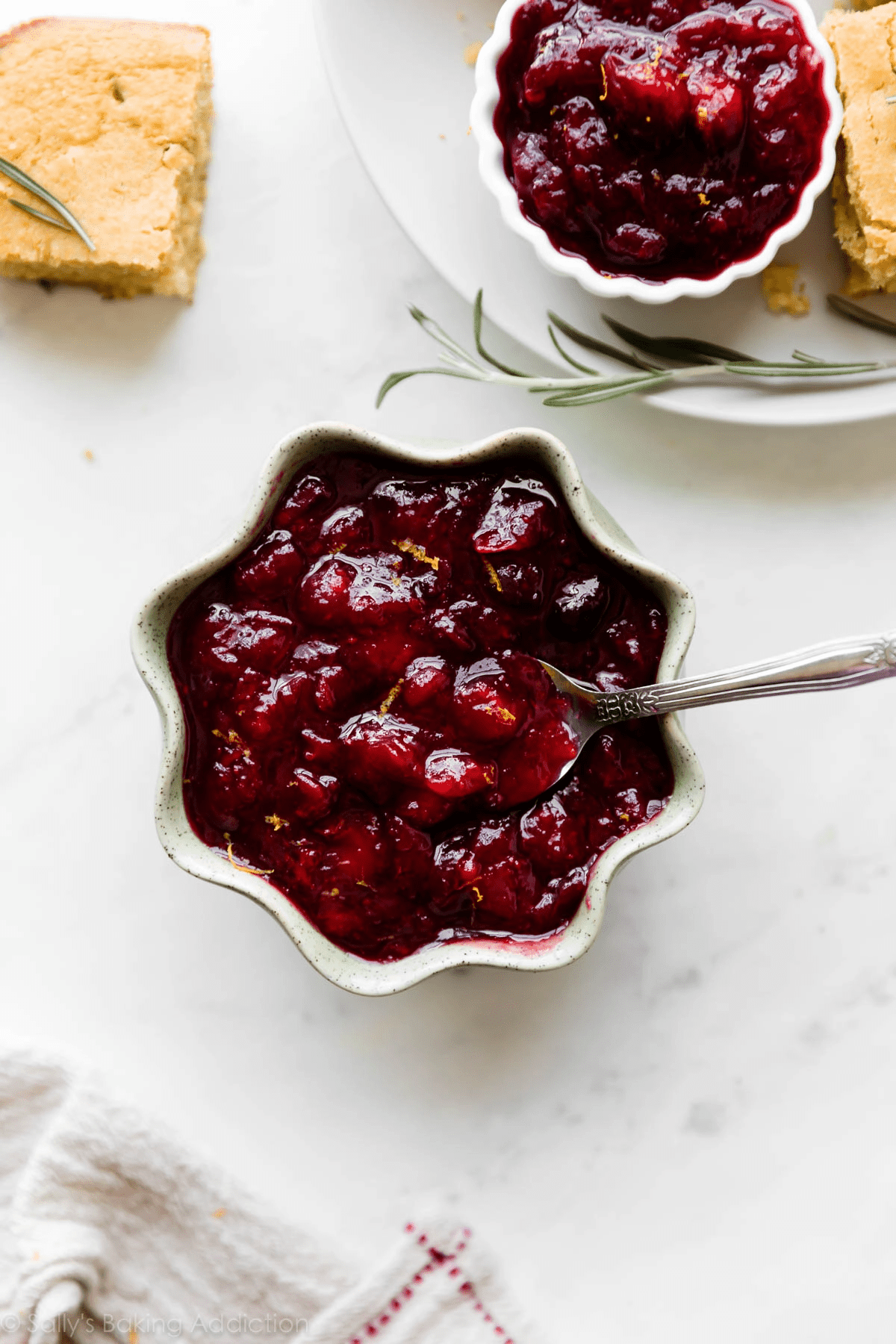 Cranberry sauce in a star ramekin on a table with another small portion of cranberry sauce on the side. 