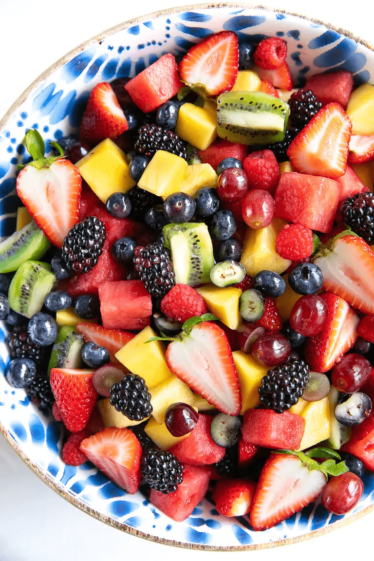 Fruit Salad Recipe is made with fresh, ripe fruit and drizzled with a light orange juice dressing in a blue and white patterned bowl. 