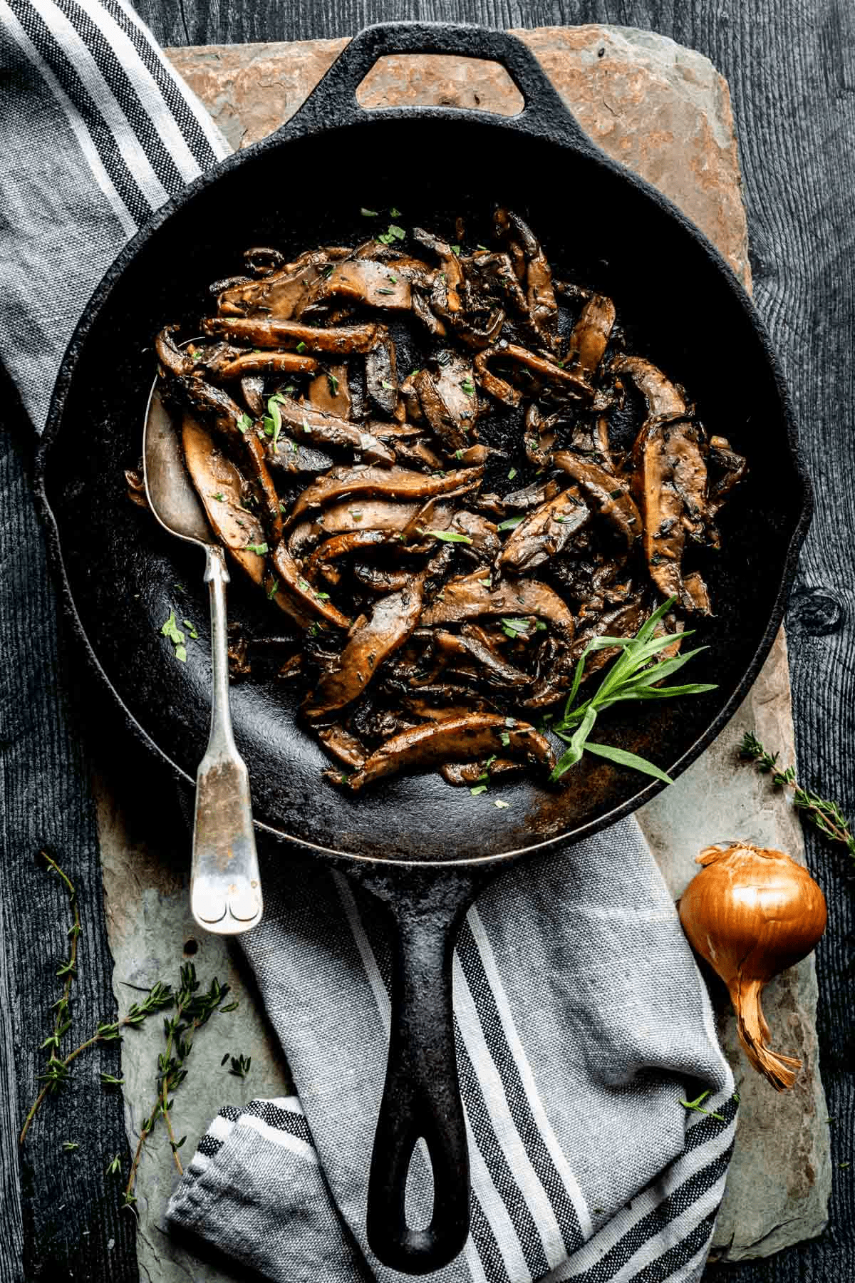 Pottobello Mushrooms cooked in a skillet with a spoon in the pan, on a table. 