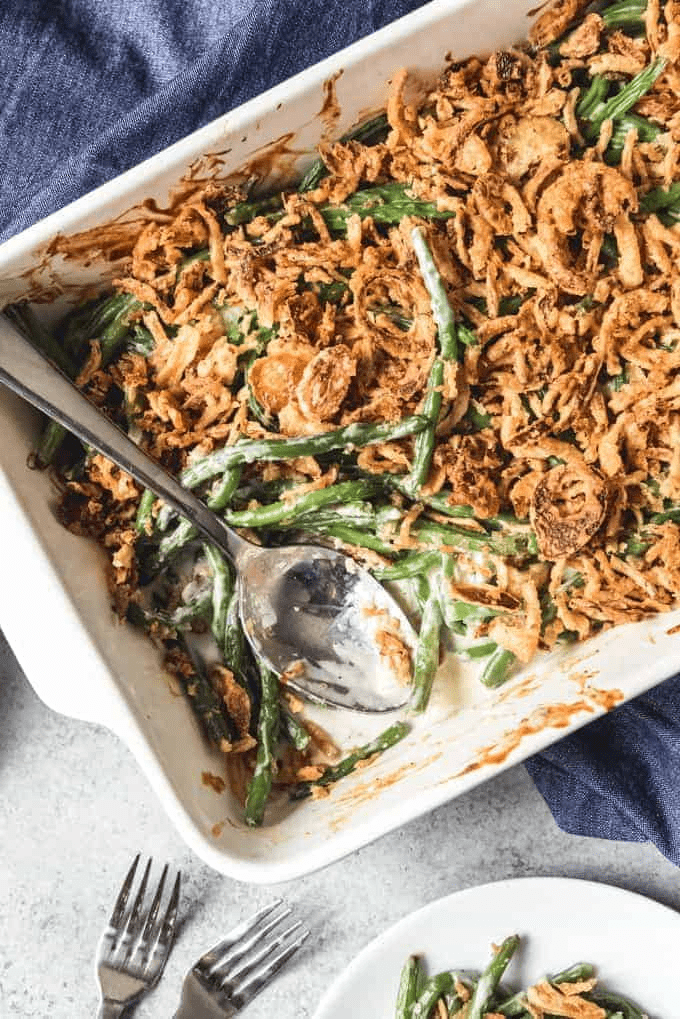 Green bean casserole in a white dish with a spoon in in. 