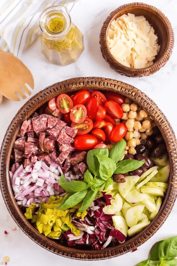 Top view of Italian chopped salad in a brown wooden bowl on a table. 