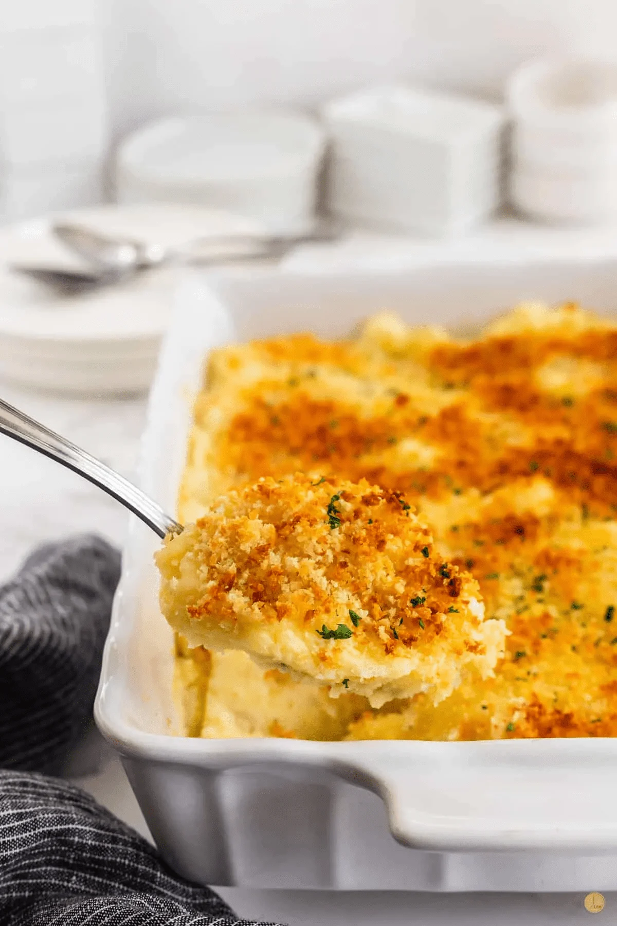 Mashed potato gratin in a white dish with a spoon lifting a portion out.