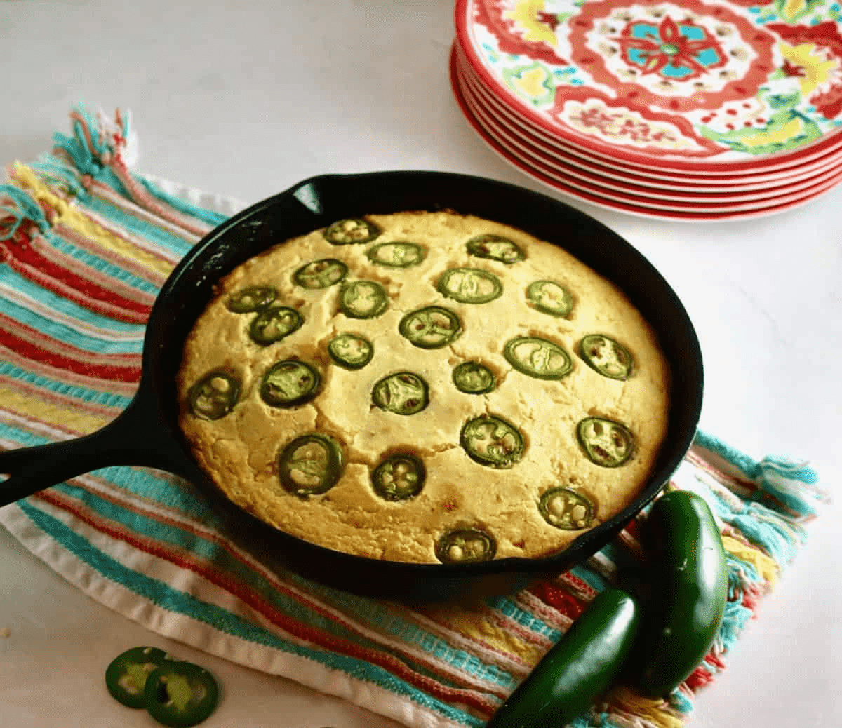 Cornbread in a skillet with Jalapenos on it. 