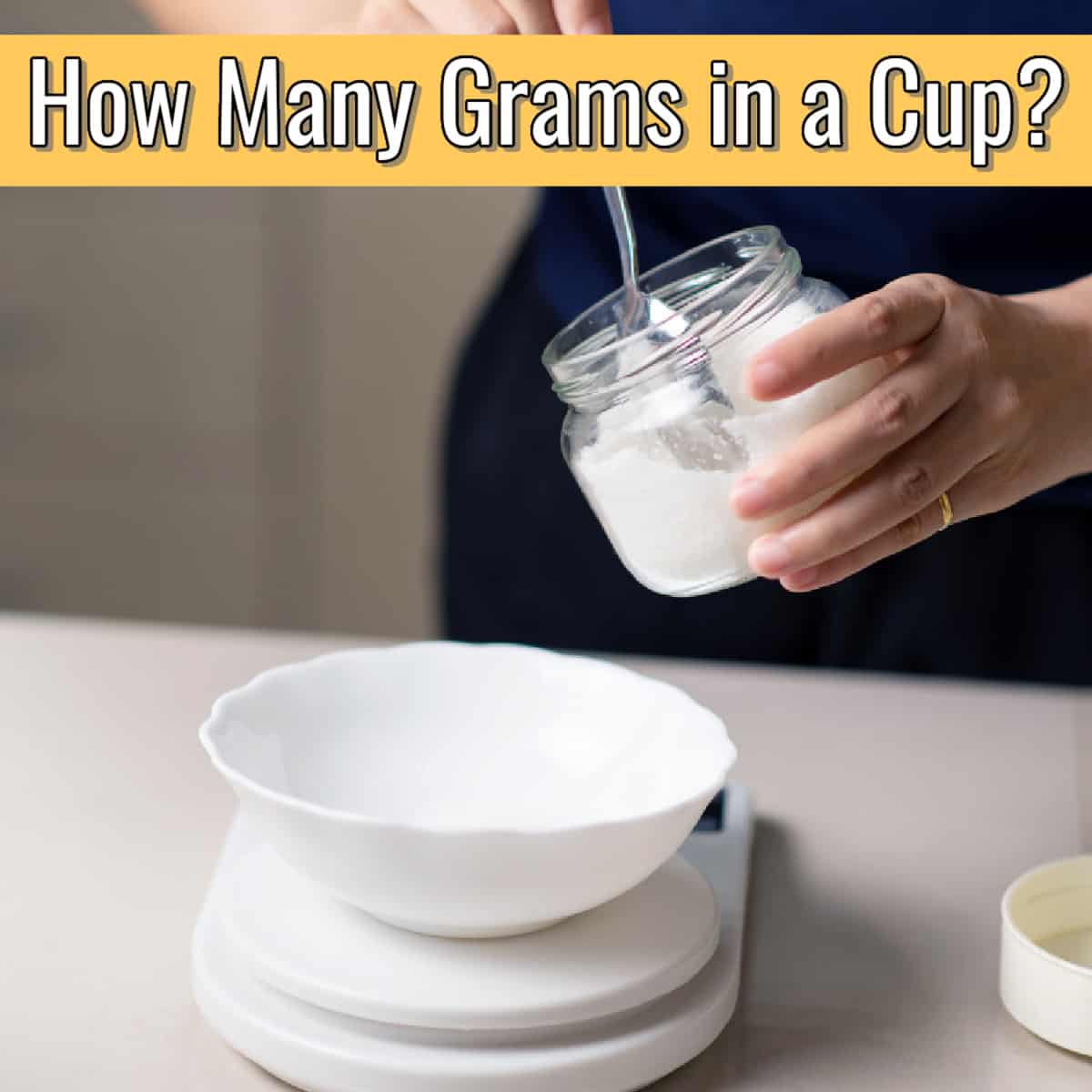 spoon and jar of sugar and a kitchen scale measuring how many grams are in a cup