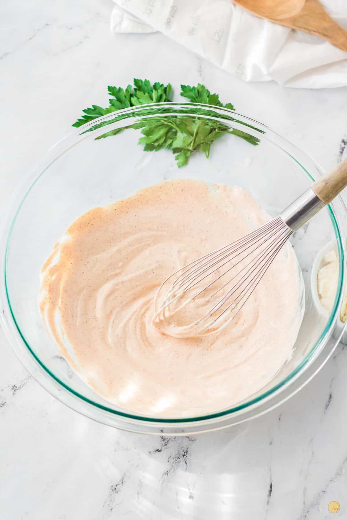 clear bowl of dressing with whisk