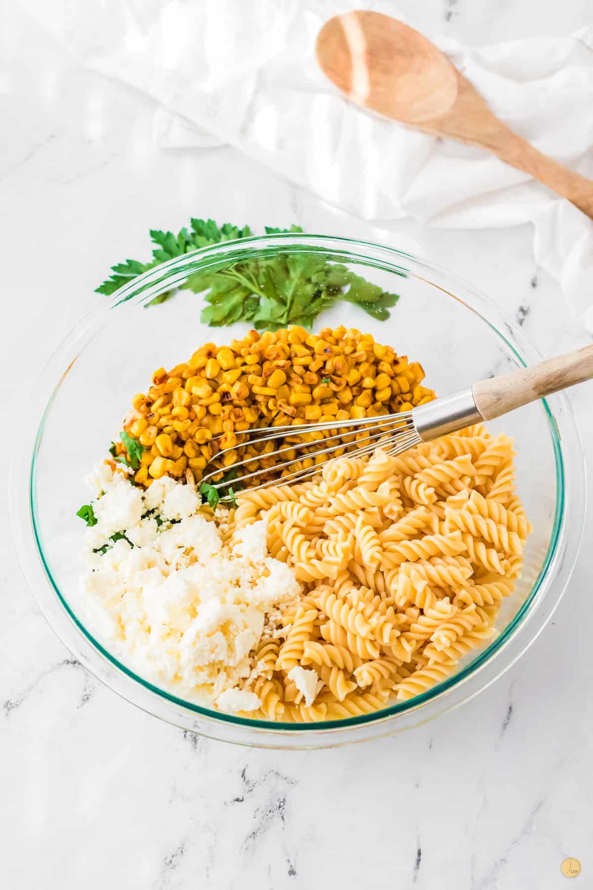 bowl of pasta noodles, corn, and cheese with a whisk