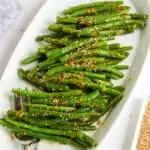 White oval plate filled with Spicy green beans.